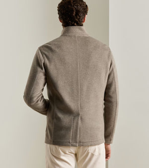 Back view of a man wearing a tan Peter Millar Crown Flex Merino blazer with a stand collar.