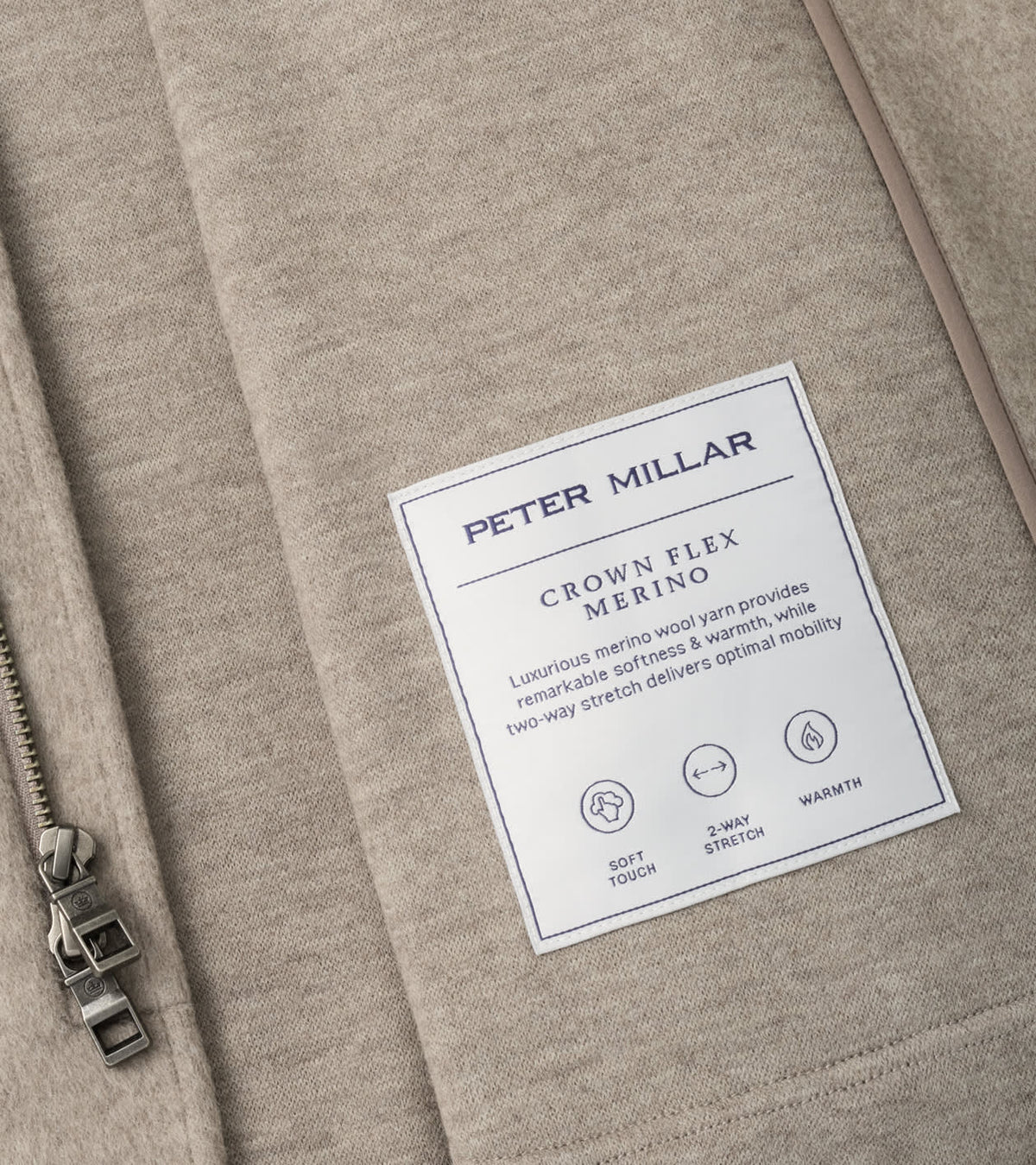 Close-up of the tan interior of a Peter Millar Crown Flex Merino Blazer, highlighting the product label with material details and icons for soft touch, two-way stretch, and warmth.