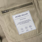 Peter Millar Bedford Quilted Vest in tan with midweight insulation, featuring a zippered pocket and a rectangular interior label detailing its warmth, wind resistance, and soft touch.