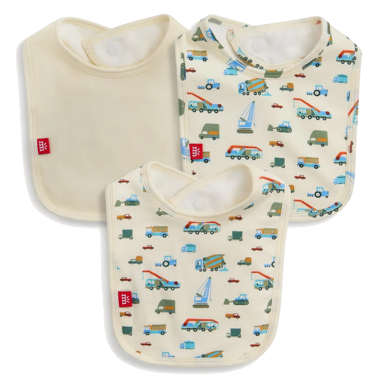 The Magnetic Me Dumps Like A Truck Modal Bib 3-Pack includes one solid cream and two vehicle-patterned bibs (cars, trucks, buses), all with white trim and red logo tags. Made from soft, eco-friendly modal for baby's comfort.