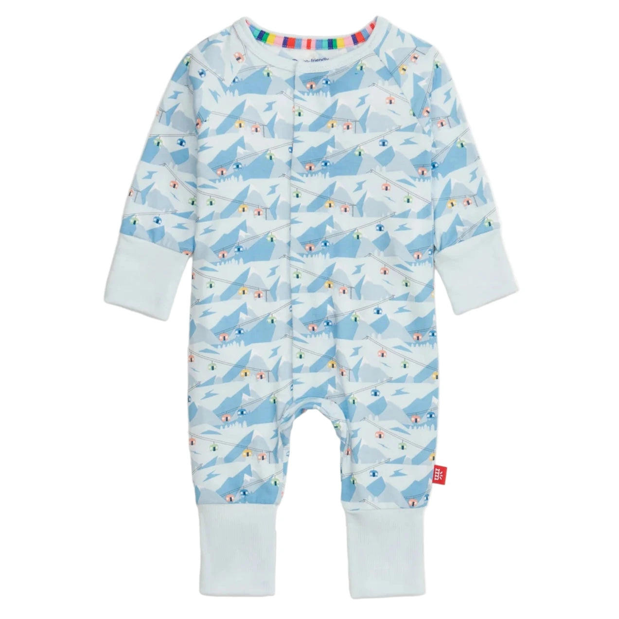 The Magnetic Me Baby Apres Chic Modal Convertible Coverall features a light blue mountain and skier pattern, sustainable modal fabric, light blue cuffs, multicolor stripe collar lining, and easy magnetic closures.