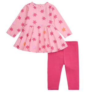 The Magnetic Me Baby Girls' and Girls' Cosmic Confetti Dress & Legging Set features a pink long-sleeve organic cotton dress with red and orange star prints and coordinating solid pink leggings, shown on a white background.