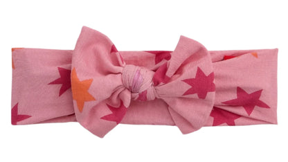 The Baby Girls' Cosmic Confetti Bow Headband by Magnetic Me is a pink modal headband with red and orange star patterns—a delightful accessory for your little one.