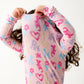 A child pulls the Baby and Kids' Party Animals Glow in the Dark Modal Magnetic PJ Set by Magnetic Me over their head, face partially covered—colorful animal and heart prints make bedtime dressing fun and easy.