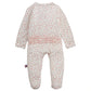 Introducing the Magnetic Me Baby Girls' Apple Blossom Modal Ruffle Footie—a cozy white baby onesie crafted from soft modal, featuring long sleeves, an adorable pink apple blossom print, and charming ruffle detail across the back. Designed for comfort, it also includes a small striped tag on the left side.