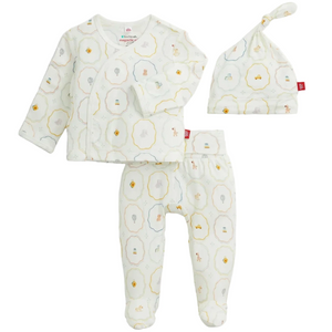 The Magnetic Me Baby Nursery Magic Cream Modal Take Me Home Set includes a three-piece ensemble: a long-sleeve kimono wrap-style shirt, footed pants, and a hat, all made from soft modal fabric in white and adorned with delicate pastel animal and object prints.