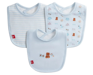 The Magnetic Me Nursery Nostalgia Modal Bib 3-Pack is displayed, featuring three eco-friendly blue baby bibs: one with stripes, one with animal illustrations, and a magnetic bib adorned with embroidered teddy bear and bow designs on the front.