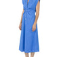 A person wearing the Callas Milano Miami Dress, a sleeveless blue midi shirt dress with a collar, paired with black flip-flops, stands against a white background.