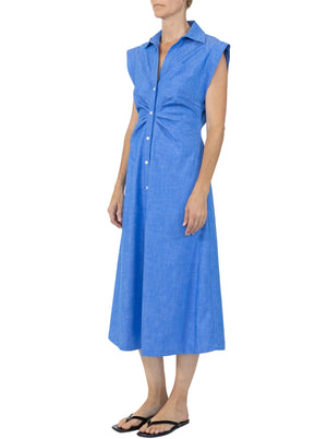 A person wearing the Callas Milano Miami Dress, a sleeveless blue midi shirt dress with a collar, paired with black flip-flops, stands against a white background.