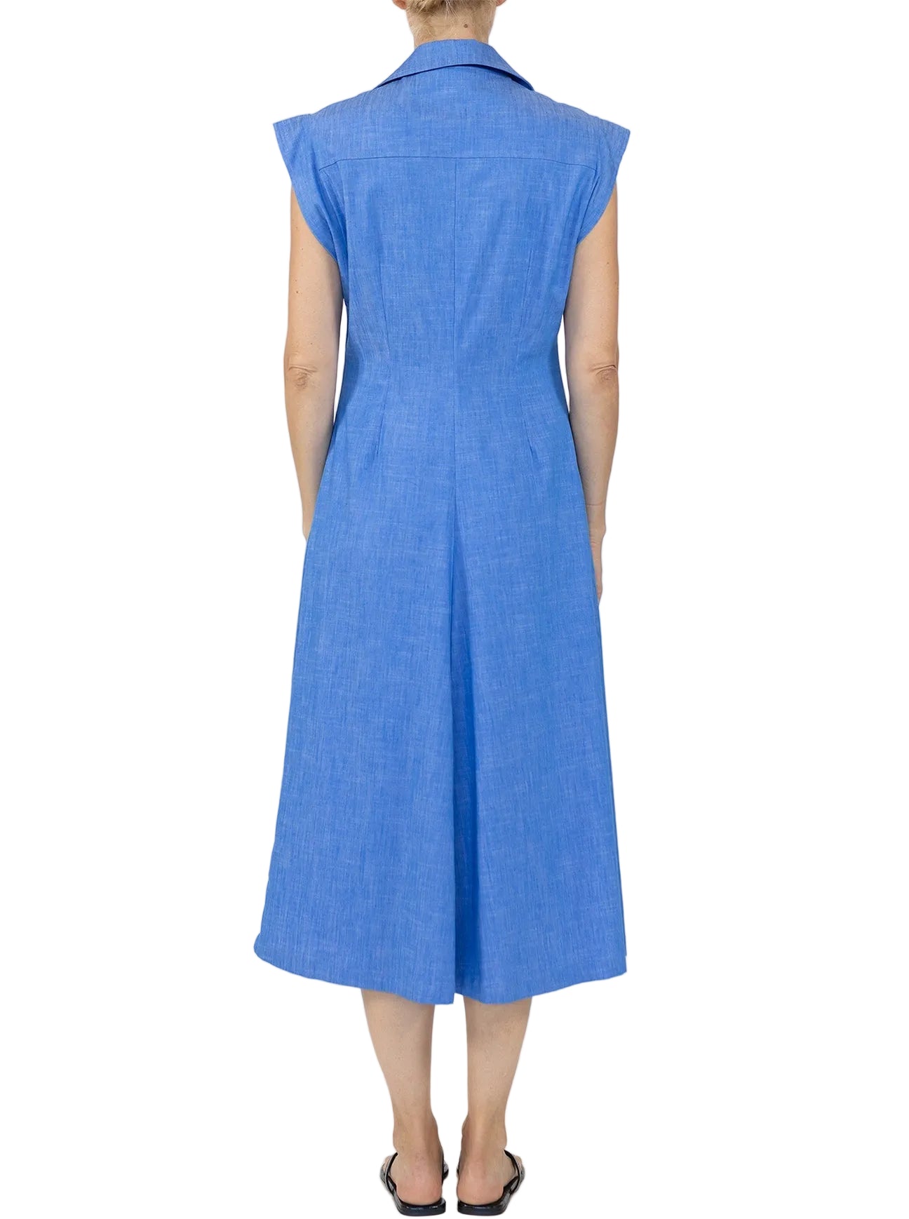 A person is shown from the back against a white background wearing the Callas Milano Miami Dress, a sleeveless knee-length stretch chambray piece, paired with black sandals.