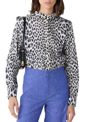 A person wearing the Callas Milano Mika Top in black and white cheetah print, tucked into high-waisted blue pants, paired with a black shoulder bag.