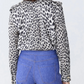 A person is shown from the back wearing the Callas Milano Mika Top, a black-and-white cheetah print shirt, paired with long-sleeve high-waisted blue jeans.