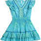 A Poupette St Barth Girls' Camila Mini Dress in light teal with blue and green geometric patterns, featuring butterfly sleeves, a V-neckline, and a flounced hem.