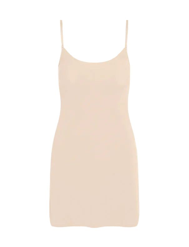The Commando Classic Mini Cami Slip is a sleeveless, light beige dress with thin straps and a scoop neck, featuring a weighted hem for drape—ideal for layering under dresses. Shown on a plain white background.