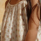 A child wearing the Konges Slojd Girls’ Coco Strap Dress stands outdoors, with long brown hair draped over one shoulder.