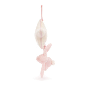 A perfect newborn gift, this Jellycat Bashful Blush Bunny Musical Pull is a pink plush hanging upside down from a white carrot with a pink string.