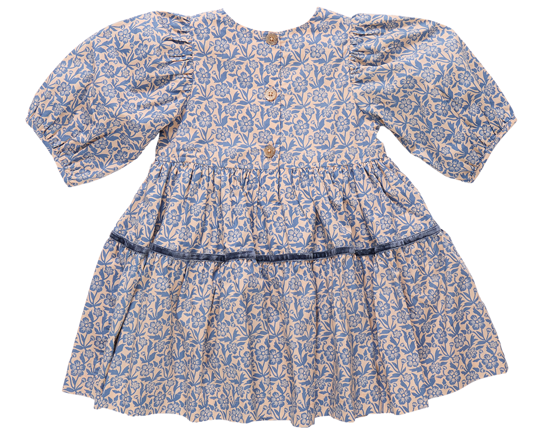 The Girls' Maribelle Dress by Pink Chicken showcases a blue climbing floral print on cotton poplin, puff sleeves, three wooden back buttons, and a gathered skirt with a dark blue ribbon at the waist.