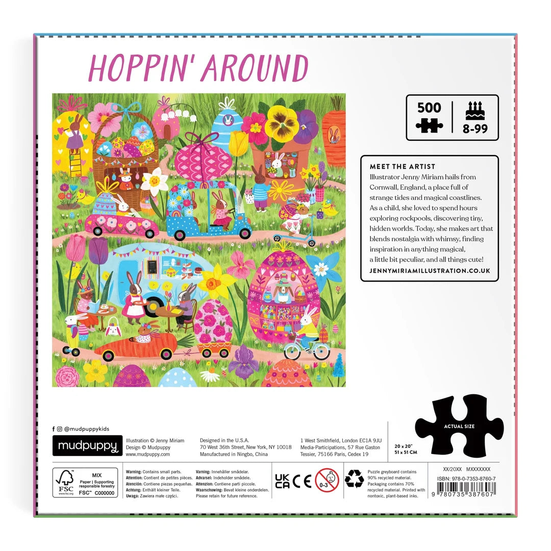 The Family Hoppin’ Around Puzzle by Chronicle Books features a colorful illustrated box depicting a whimsical spring scene with rabbits, flowers, decorated eggs, and houses. Designed by Jenny Miriam, this delightful 500-piece puzzle is perfect for ages 8-99 and promises family fun and springtime enjoyment.