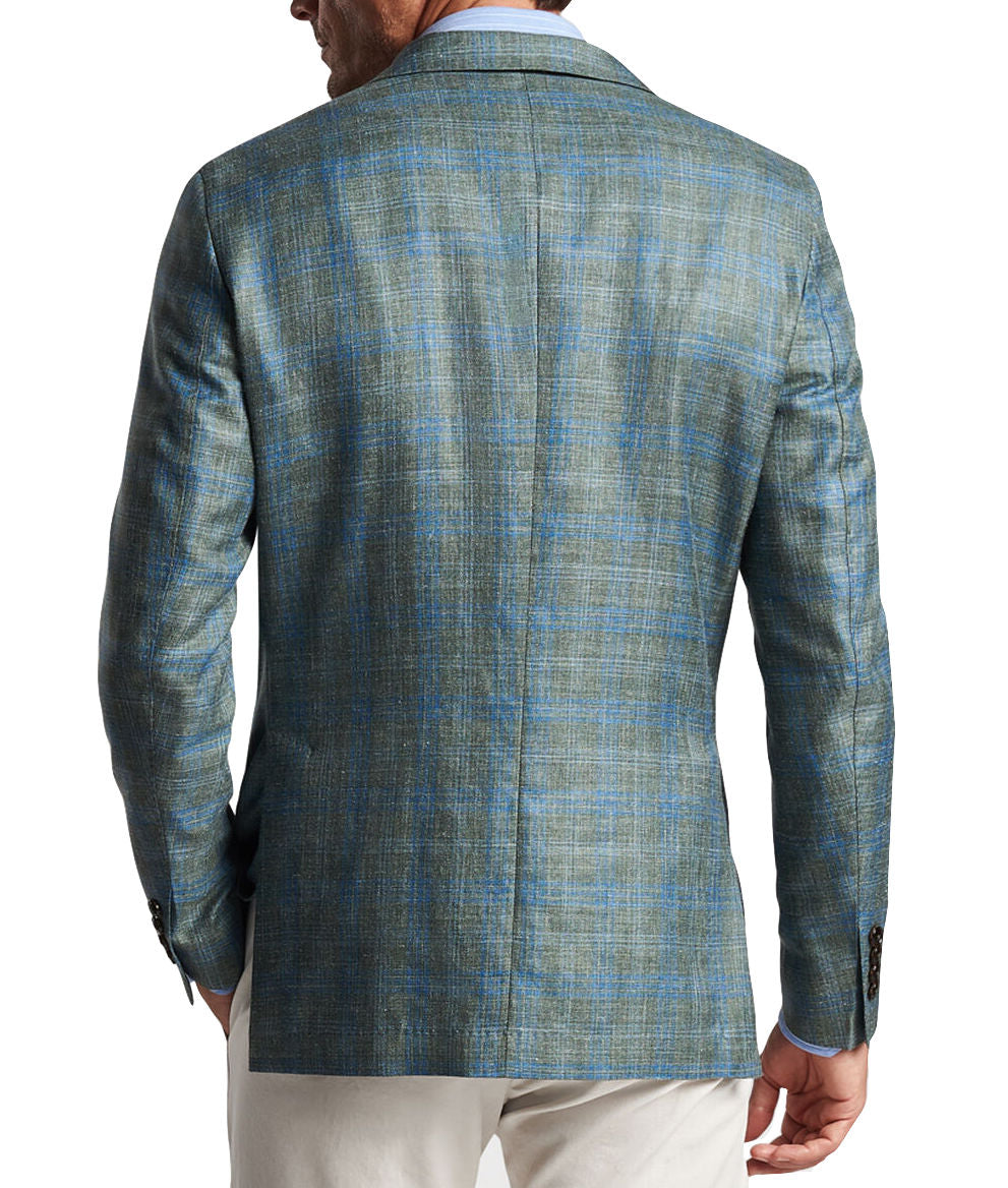 A man, seen from the back, is sporting the Peter Millar Tremont Plaid Soft Jacket in blue and green over a light blue shirt. The jacket, crafted from Italian wool by Peter Millar, complements his light-colored pants perfectly.