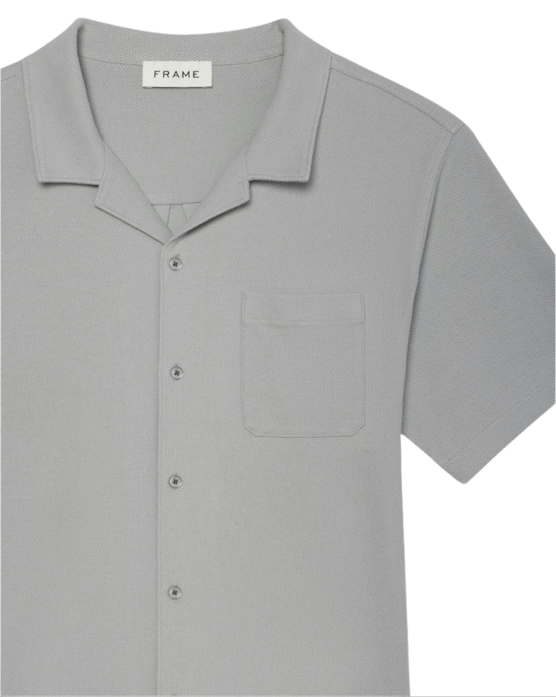The Jacquard Short Sleeve Relaxed Shirt by Frame is a light grey men's shirt in textured cotton, featuring a notched collar, chest pocket, and an inner "FRAME" label.