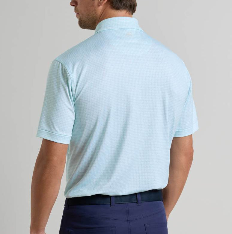 A man is shown from the back wearing a light blue Peter Millar Ashgrove Performance Jersey Polo and dark blue pants against a plain background.