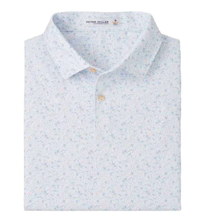 The Peter Millar Featherweight Land Of The Free Performance Polo in light blue features a subtle floral print, four-way stretch for comfort, and is neatly folded with its collar and buttons visible.