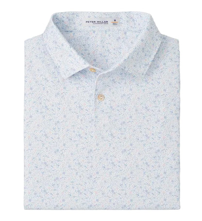 The Peter Millar Featherweight Land Of The Free Performance Polo in light blue features a subtle floral print, four-way stretch for comfort, and is neatly folded with its collar and buttons visible.