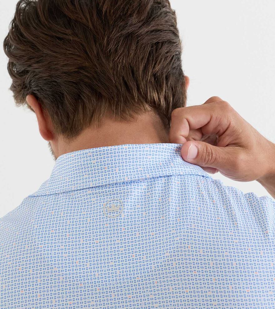 A person seen from behind lifts the collar of a Peter Millar Alta Performance Jersey Polo in light blue pattern with their right hand, highlighting its four-way stretch material.