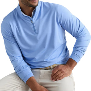 A man wearing the Peter Millar Perth Mélange Performance Quarter-Zip in light blue with beige pants, seated with one arm resting on his knee.