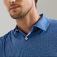 A man wearing the Peter Millar Featherweight Headcovers Performance Polo, a blue patterned, lightweight shirt with white buttons and UPF 50+ sun protection, shown from the chest up.