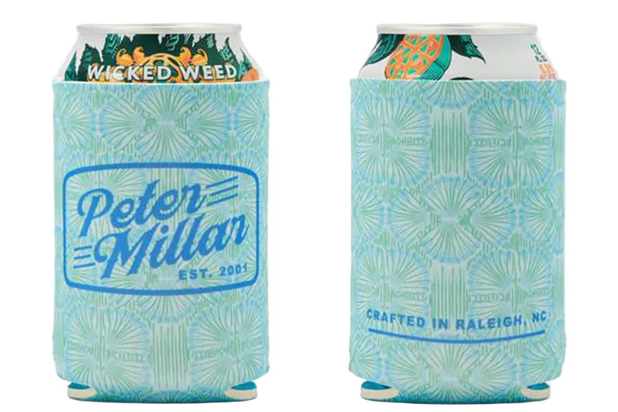 Two cans with light blue koozies inspired by Peter Millar’s Tide Lines Swim Trunk; one side reads "Peter Millar EST. 2001," the other "CRAFTED IN RALEIGH, NC." Partial drink branding shows through the quick-dry fabric design.