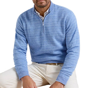 A man wears the Peter Millar Saratoga Striped Quarter-Zip Sweater over a collared shirt and white pants, seated with his upper body visible against a white background.
