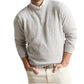 A person wearing the Peter Millar Montauk Crewneck Sweater in light gray over a white collared shirt and light beige pants, with hands in their pockets.