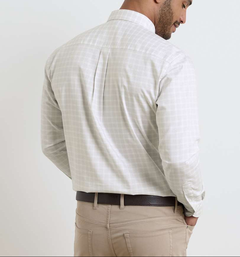 A man stands facing away, wearing the Peter Millar Douglas Crown Lite Cotton-Stretch Sport Shirt in a light plaid, tucked into beige pants with a dark brown belt.