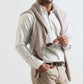 A man in a Peter Millar Douglas Crown Lite Cotton-Stretch Sport Shirt, beige stretch cotton pants, and a sweater over his shoulders holds sunglasses in his right hand and smiles.