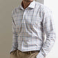 A man wears the Peter Millar Warren Crown Lite Cotton-Stretch Sport Shirt with beige trousers, standing hands in pockets against a neutral background.