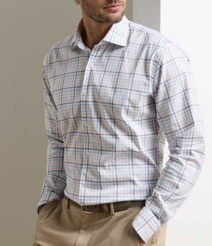 A man wears the Peter Millar Warren Crown Lite Cotton-Stretch Sport Shirt with beige trousers, standing hands in pockets against a neutral background.