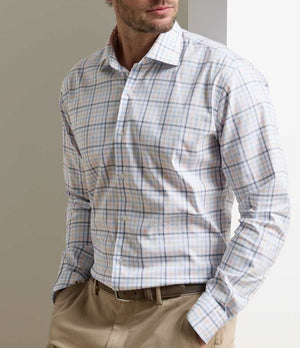 A man wears the Peter Millar Warren Crown Lite Cotton-Stretch Sport Shirt with beige trousers, standing hands in pockets against a neutral background.