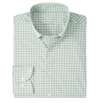 The folded Lewis Performance Twill Sport Shirt by Peter Millar is green and white checkered, features a collar and single cuff, and is crafted from performance fabric with UPF 50+ protection.