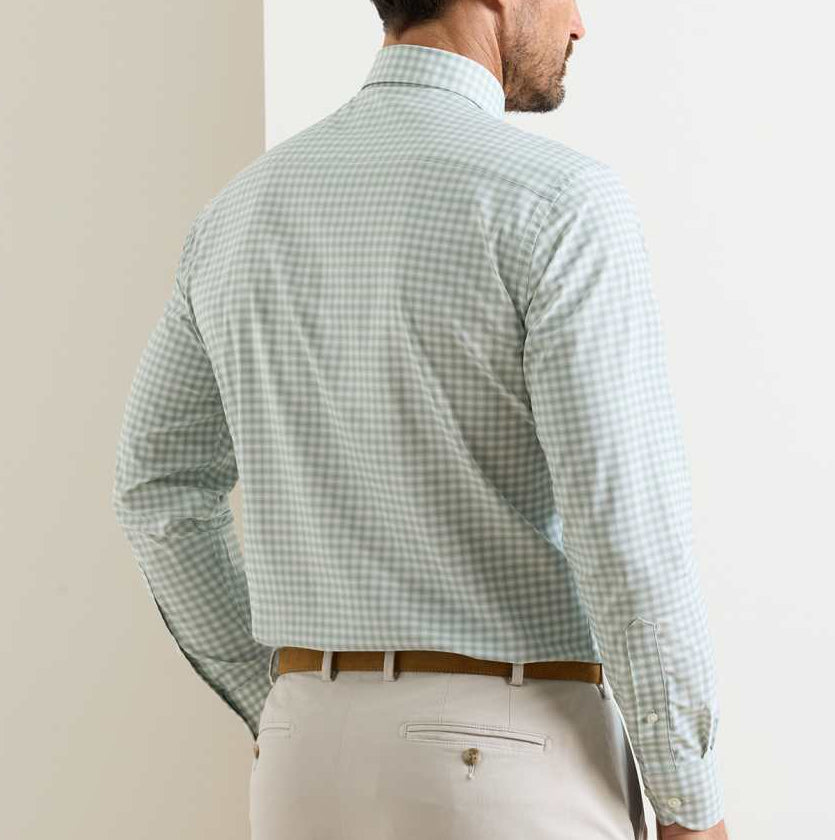 A man wearing the Peter Millar Lewis Performance Twill Sport Shirt in light green check with UPF 50+ and beige trousers stands with his back to the camera.