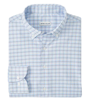 The Casey Performance Twill Sport Shirt by Peter Millar is a neatly folded long-sleeve button-down in light blue and white plaid, crafted from performance fabric. The label inside the collar reads "Peter Millar.