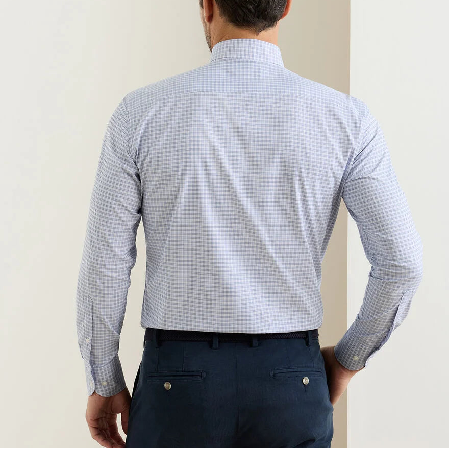 A man is seen from behind wearing the Peter Millar Phillip Performance Twill Sport Shirt in light blue checks and navy dress pants, standing before a light-colored wall.