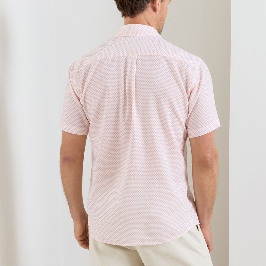 Man wearing a Peter Millar Tamarama Cotton Lyocell Sport Shirt in light pink with beige pants, facing away from the camera against a plain indoor background.