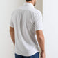 A man stands with his back to the camera, wearing the Peter Millar Seaward Cotton Lyocell Sport Shirt in white and blue pants, set against a plain white background.