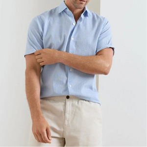 A man wearing the Peter Millar Coastal Stripe Sport Shirt stands against a plain background, adjusting his sleeve.