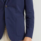 A person wearing the Peter Millar Bingham Performance Blazer in navy over a striped shirt and beige pants, with only their torso and right arm visible.