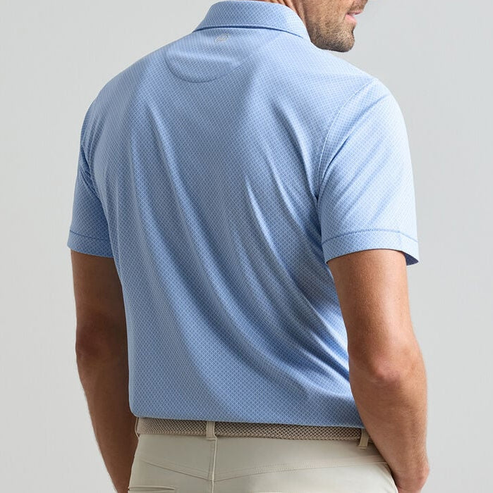 A man shown from the back against a plain background wears the Peter Millar Granada Performance Jersey Polo in light blue with short sleeves and four-way stretch, paired with beige pants.