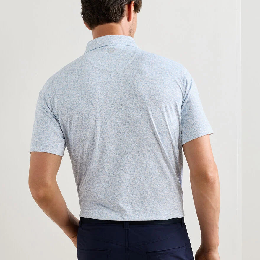 A man faces away from the camera, wearing dark pants and a light blue Peter Millar Melody Sea Performance Jersey Polo with UPF 50+.