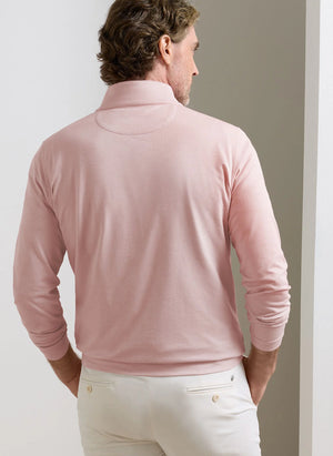 A man, seen from behind in a minimal indoor setting, wears the Peter Millar Albatross Cotton-Blend Piqué Quarter-Zip in light pink paired with white pants.