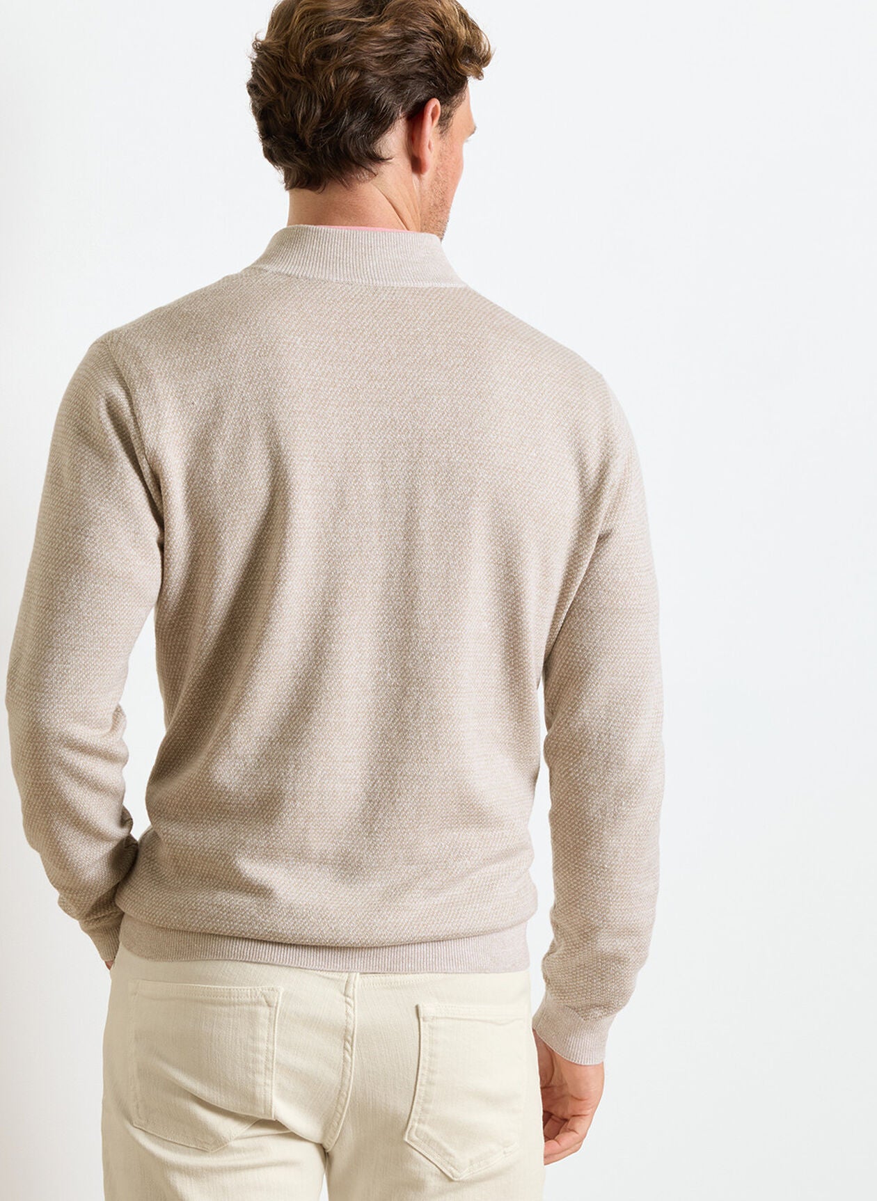 A man is shown from the back against a white background, wearing cream pants and the Peter Millar Barlow Quarter-Zip Sweater, crafted from a Merino-linen-cotton blend.